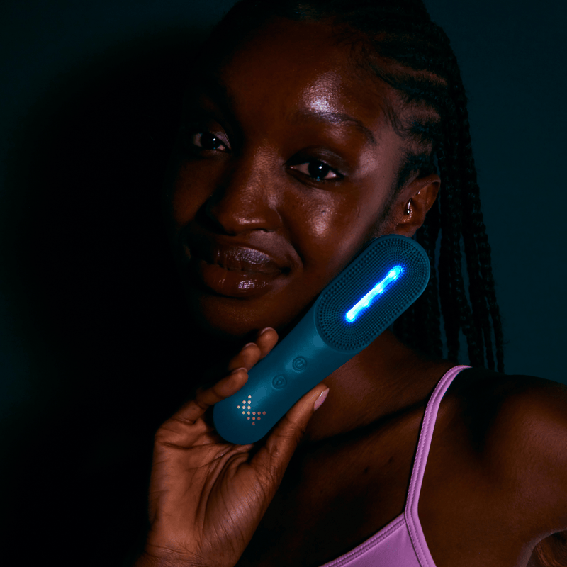 MAGNITONE XO Lights Out LED Tri Colour Micro Sonic Silicone Cleansing Brush | Model showing blue light on face